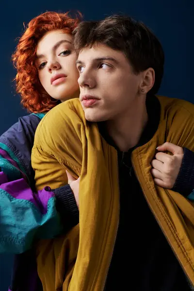 Beautiful red haired woman in vibrant clothes hugging her handsome boyfriend and looking at camera — Stock Photo