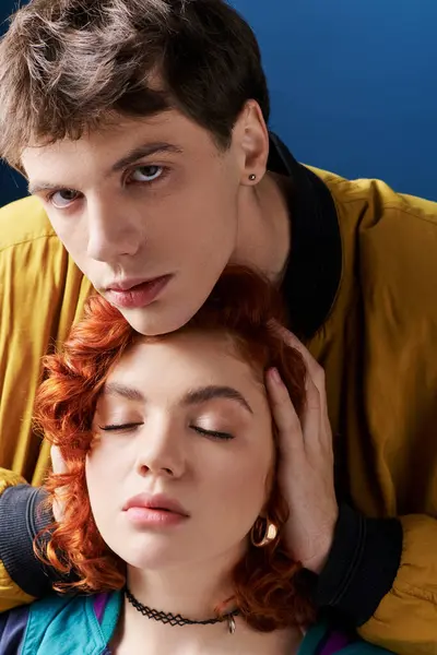 Young man in stylish attire hugging his appealing red haired girlfriend and looking at camera — Stock Photo