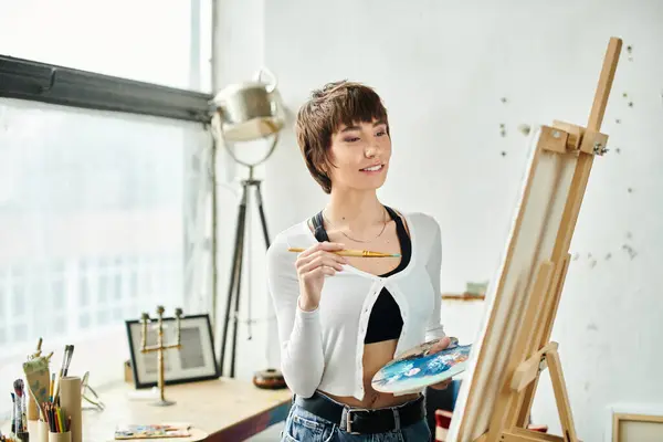 A woman holds a paintbrush and palette. — Stock Photo
