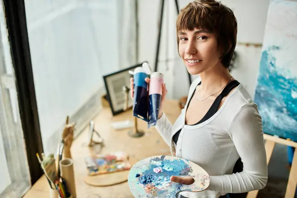 A woman skillfully holds a paintbrush and a plate. — Stock Photo
