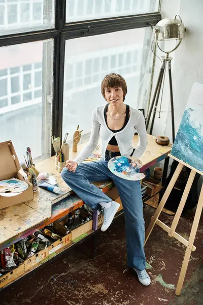 Une femme en contemplation sur une table à côté d'un tableau. — Photo de stock