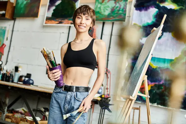 A woman in a black top holding a paintbrush. — Stock Photo