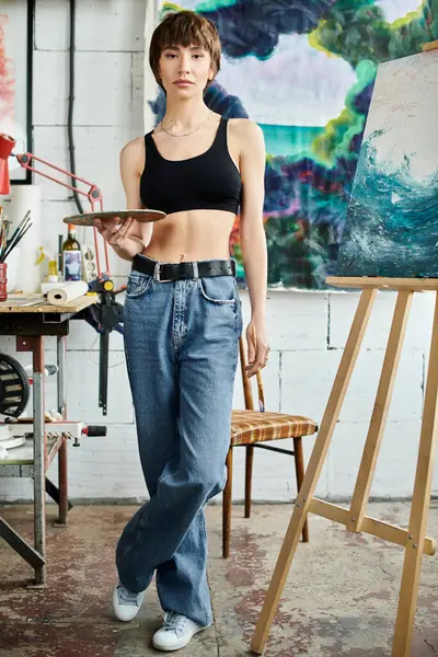 Uma mulher está na frente de uma pintura, segurando uma paleta. — Fotografia de Stock