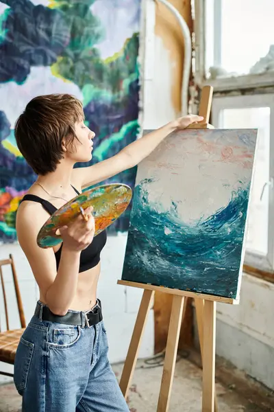 A woman with a paintbrush in hand, focused on painting a picture. — Stock Photo