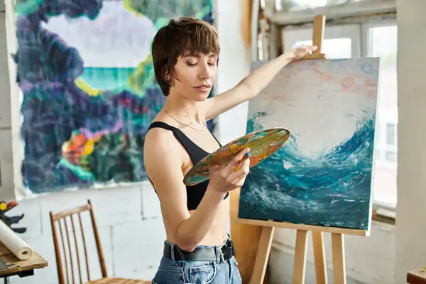 Una donna dipinge un quadro con un pennello in mano. — Foto stock
