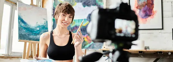 Woman in black tank top wields paintbrush. — Stock Photo