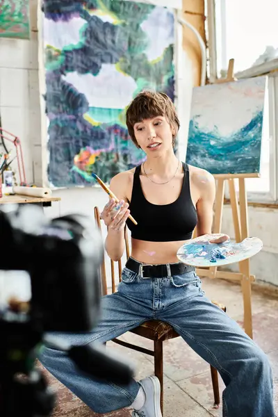 Woman captivated by paintbrush, seated in chair. — Stock Photo