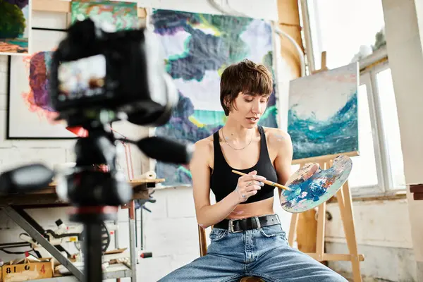 A woman, seated, paints with a brush. — Stock Photo