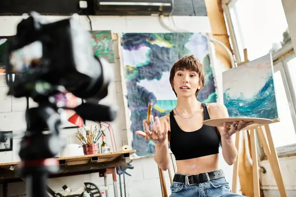 Uma mulher senta-se em uma cadeira na frente de uma pintura cativante, imersa em sua beleza. — Fotografia de Stock