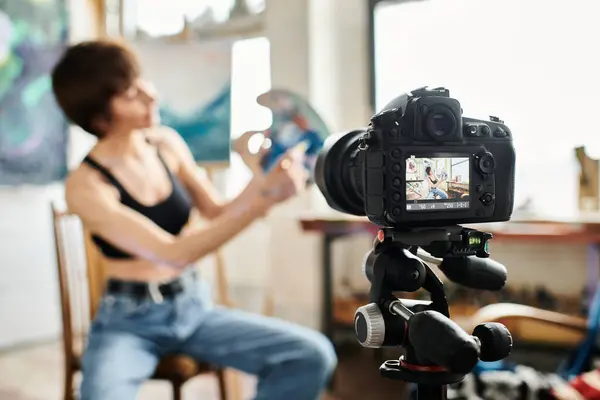 Woman sitting in chair, showing how to paint on camera. — Stock Photo