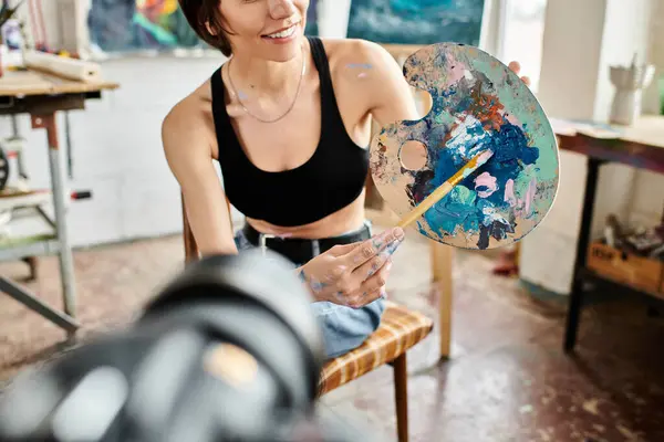 Woman seated, brush in hand, immersed in creativity. — Stock Photo