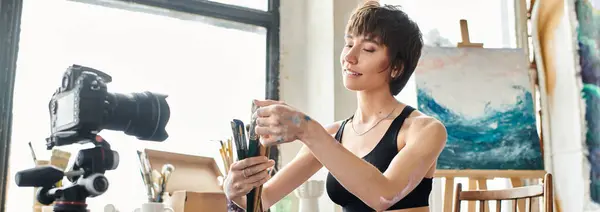 Beautiful woman sitting in chair, showing how to paint on camera. — Stock Photo