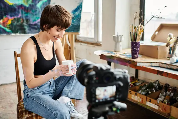 Una donna siede con grazia su una sedia, tenendo una tazza. — Foto stock