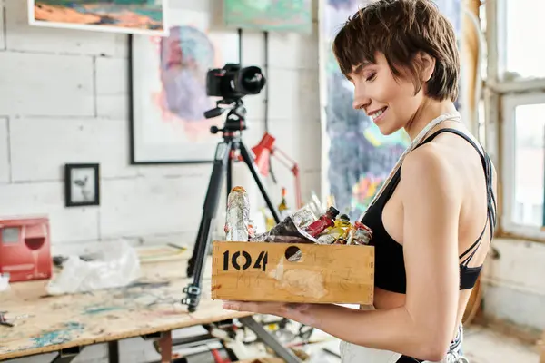 Woman showcases box of paint in front of camera. — Stock Photo