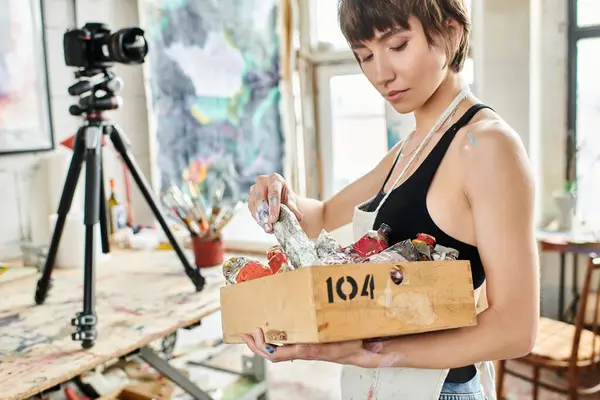 Una mujer sosteniendo una caja llena de pintura. - foto de stock