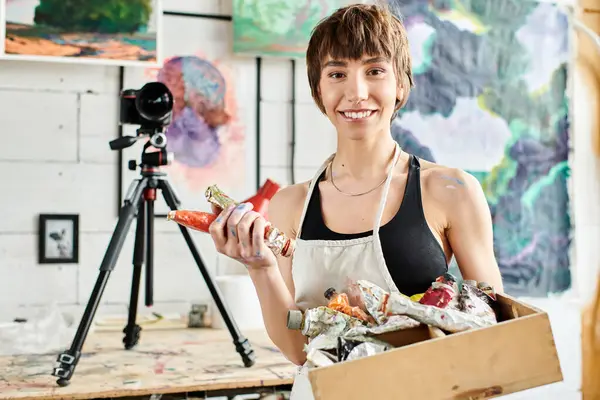 Una donna che tiene una scatola di vernice davanti a una telecamera. — Foto stock