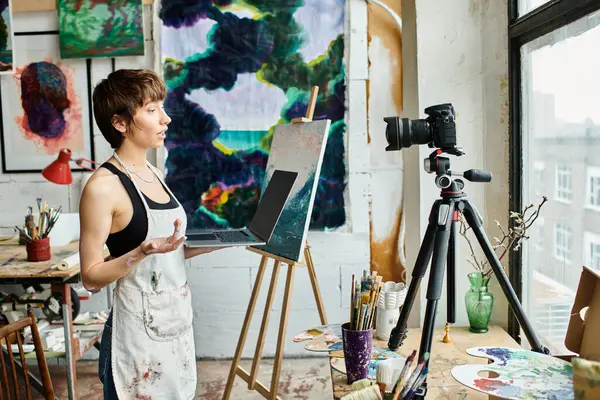 A woman standing in front of an easel with a painting. — Stock Photo