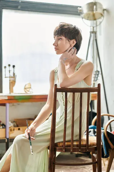 Женщина в длинном платье изящно сидит на стуле. — стоковое фото