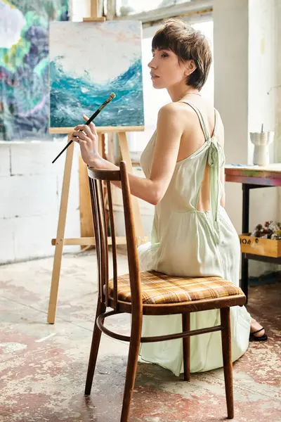 Mulher sentada na cadeira, admirando a pintura na frente. — Stock Photo