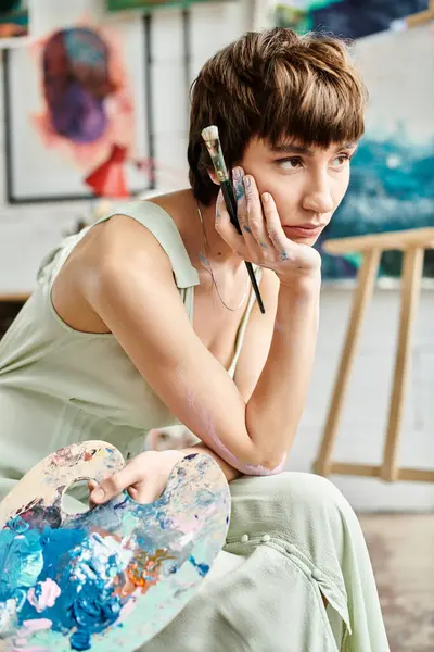 A woman in stylish attire sits in art studio. — Stock Photo