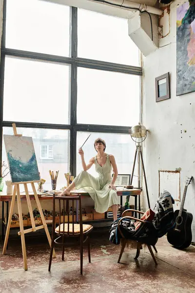 A woman sits by a large window, gazing outside. — Stock Photo