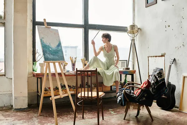 A woman sits at a table in front of a window, lost in thought and surrounded by sunlight. — Stock Photo