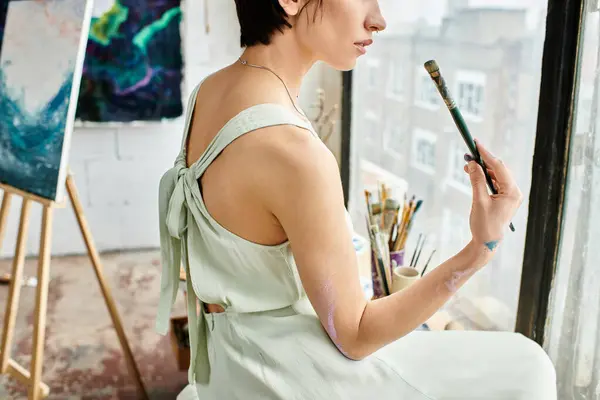 A woman in a white dress holds a paintbrush. — Stock Photo