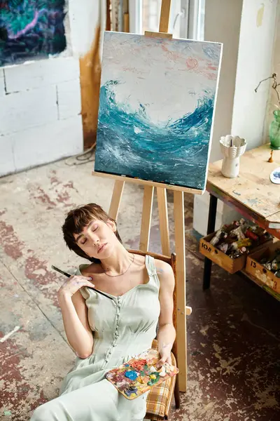 Mulher senta-se na frente da pintura. — Stock Photo