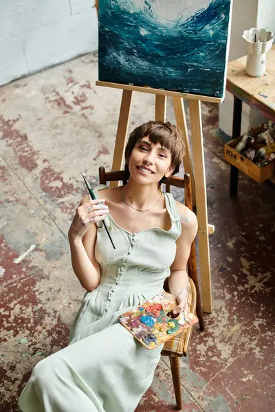 Женщина сидит в кресле, очарованная картиной, выставленной перед ней. — стоковое фото