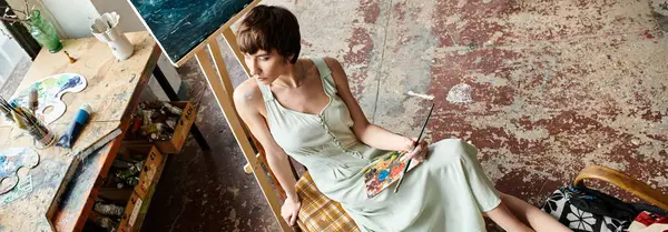 Stylish woman seated in chair, wth brush and palette. — Stock Photo