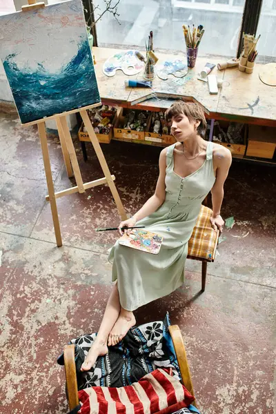 Uma mulher senta-se diante de uma pintura em uma cadeira. — Fotografia de Stock