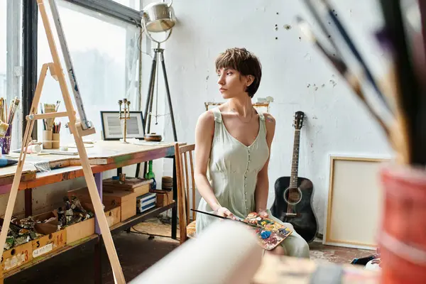 Attractive woman sits on a chair, holding a brush. — Stock Photo