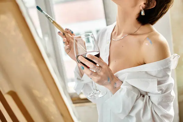 Eine anmutige Frau im weißen Kleid hält ein Glas Wein in der Hand. — Stockfoto