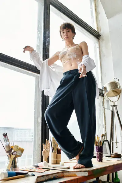 A woman stands confidently on a window sill, silhouetted against a window. — Stock Photo