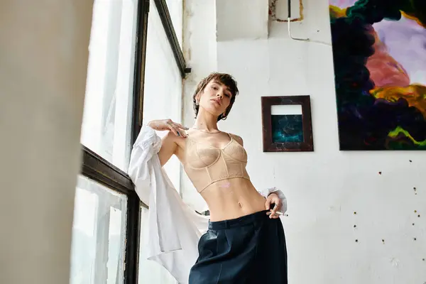 Una mujer de pie tranquilamente en una habitación cerca de una ventana. - foto de stock