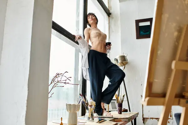 Young woman in top posing on window sill with glass of red wine. — Stock Photo