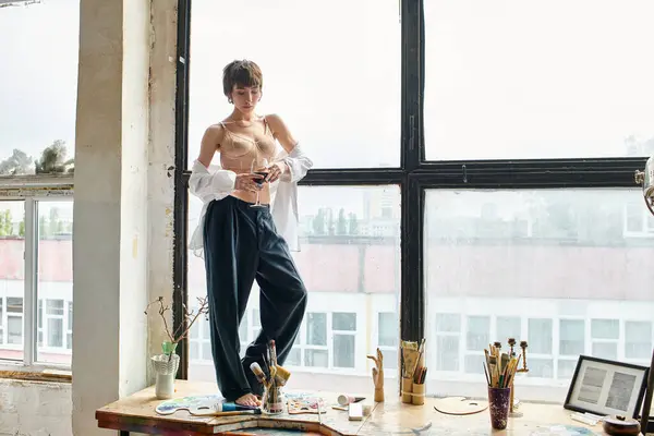 Beautiful woman in top posing on window sill with glass of red wine. — Stock Photo
