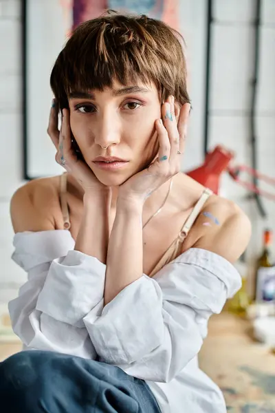 Una mujer sentada en el suelo, tocándose la cara en pensamiento. - foto de stock