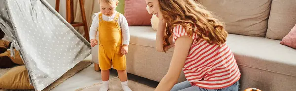 Ein junges Mädchen sitzt auf dem Boden neben ihrer kleinen Tochter und teilt einen Moment der Verbindung und spielt zu Hause zusammen. — Stockfoto