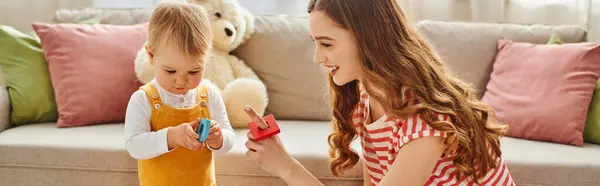 Une jeune femme et sa fille tout-petit jouent joyeusement avec un jouet, créant des souvenirs spéciaux ensemble à la maison. — Photo de stock
