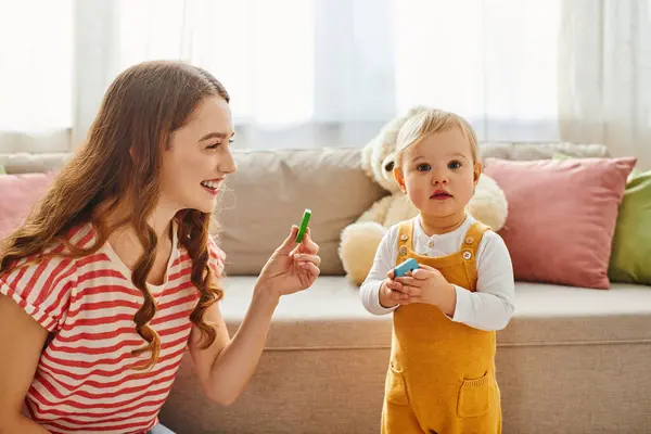 A young mother and her toddler daughter joyfully playing at home. — Stock Photo