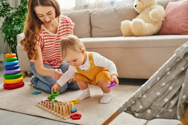 A young mother joyfully playing and interacting with her toddler daughter on the floor at home. — Stock Photo