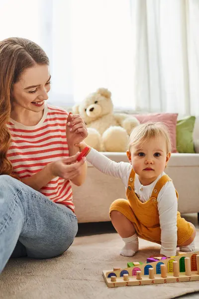 A young mother joyfully interacts with her toddler daughter while playing together on the floor at home. — Stock Photo