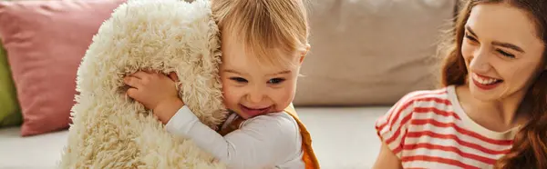 Eine junge Mutter und ihre Kleinkind-Tochter spielen fröhlich mit einem Stofftier, binden und schaffen gehegte Erinnerungen. — Stockfoto