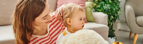 Una giovane madre e sua figlia bambina sorridono e giocano con un orsacchiotto insieme a casa. — Foto stock