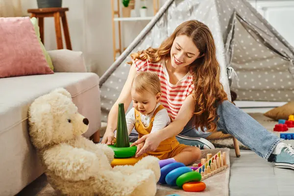 Eine junge Mutter und ihre kleine Tochter spielen mit buntem Spielzeug, binden und schaffen zu Hause Erinnerungen. — Stockfoto