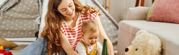 Una madre joven y su hija pequeña participan en actividades lúdicas con juguetes, disfrutando de un tiempo de calidad juntos en casa. - foto de stock