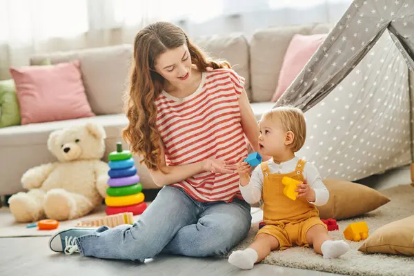 A young girl sits on the floor, engrossed in play with a toddler, sharing joyful moments in a home setting. — Stock Photo