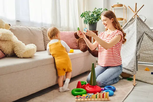 A young mother and her toddler daughter laughing and playing in a warm and inviting living room. — Stock Photo