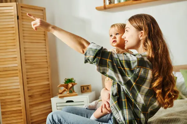 A mother and her toddler daughter pointing with excitement at something off-screen. — Stock Photo